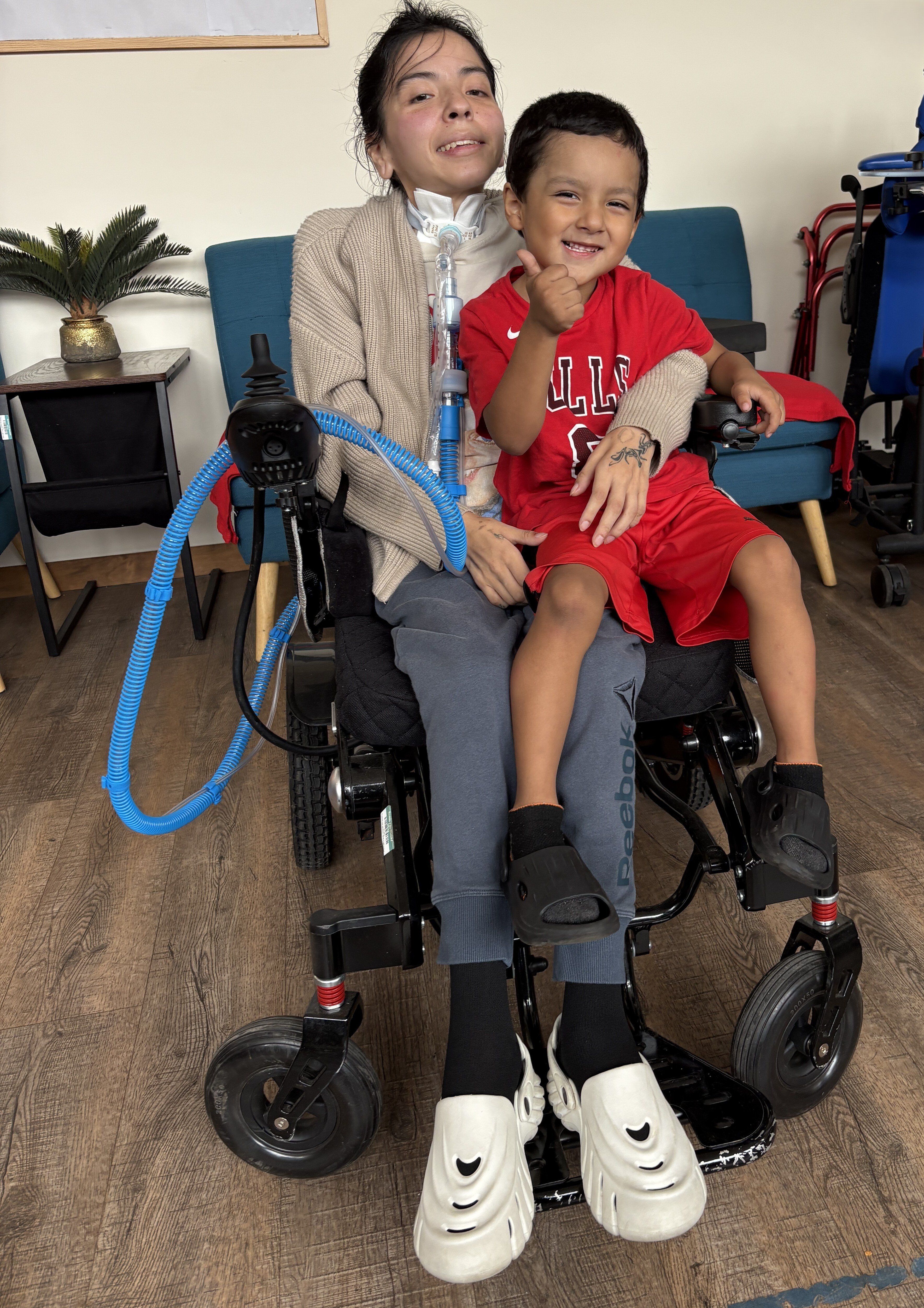 Maria and her son try out her new power wheelchair - it's a thumbs up!