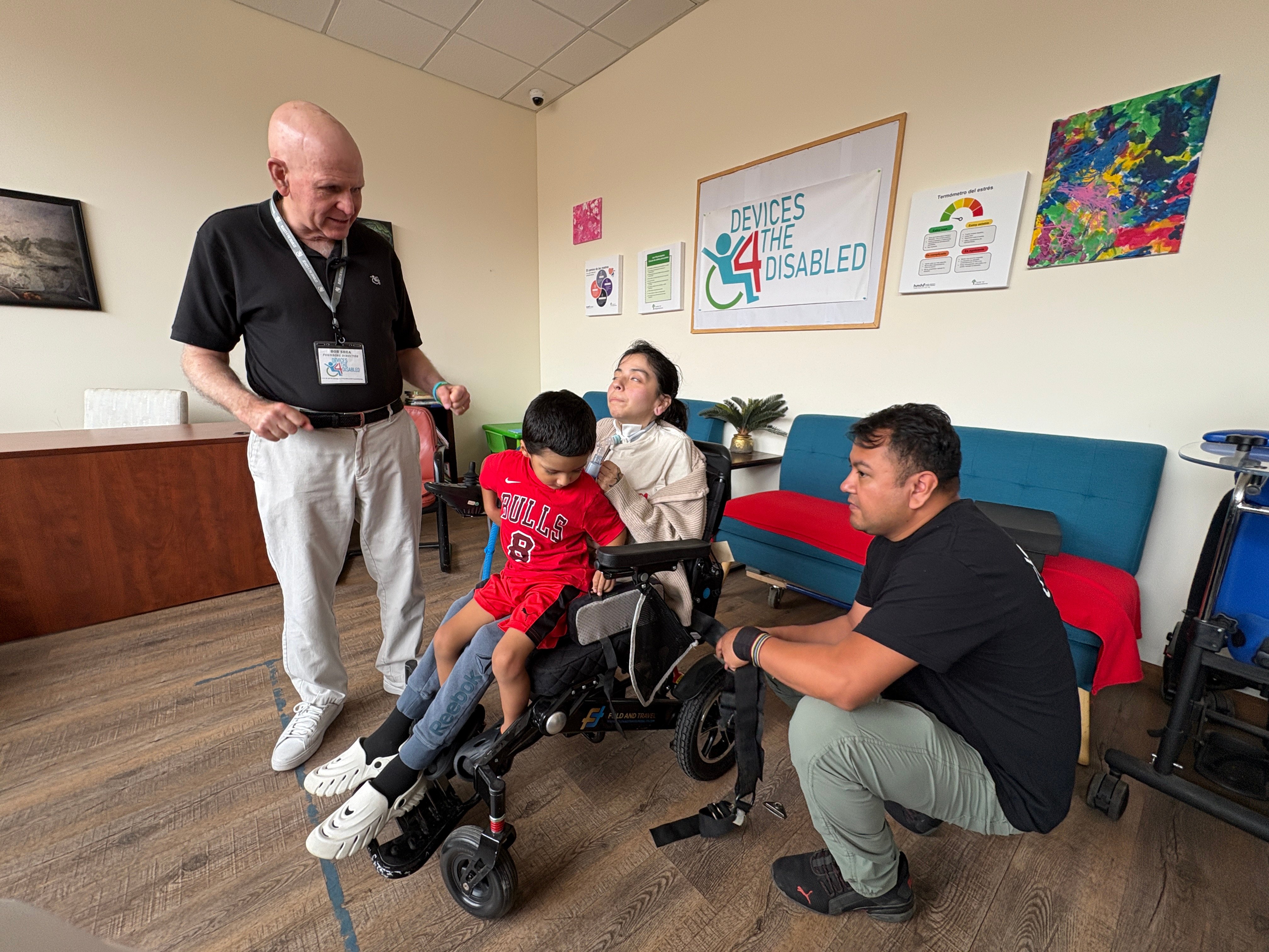 Emiliano makes adjustments to Maria's new power wheelchair